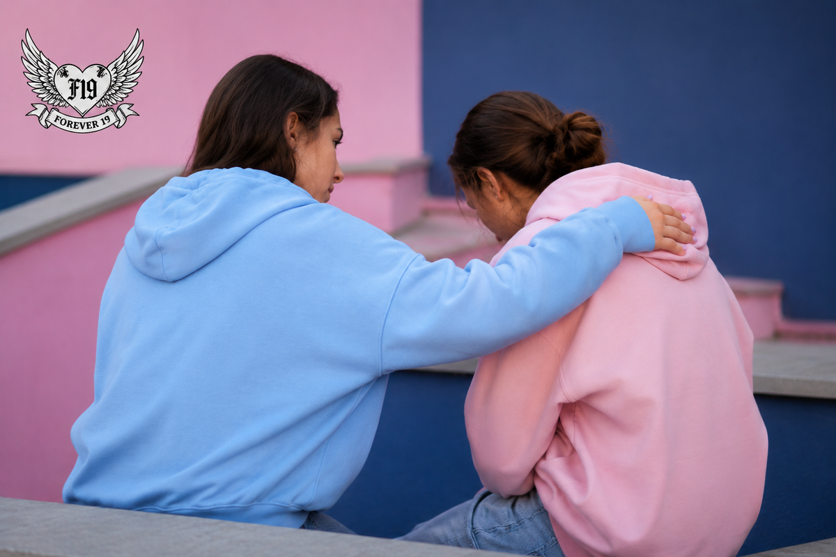 Two young people sitting together, one offering support to a friend, representing friendship and mental health support for young people.